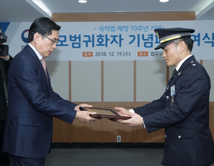 Lee Dongbin (dcha.), uno de los naturalizados ejemplares está recibiendo la placa de premio desde el ministro de Justicia en el mismo evento celebrado en el Complejo Gubernamental de Gwacheon, el 19 de diciembre.